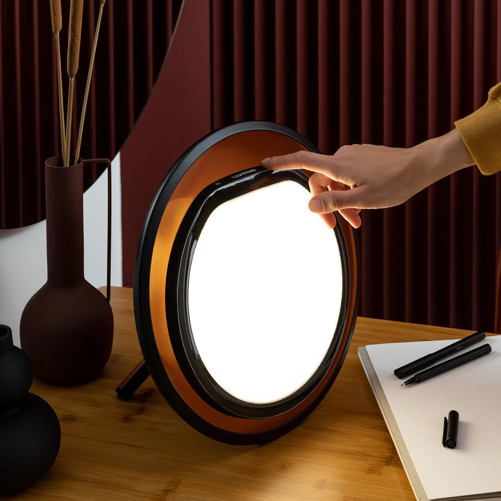 Lampe Lumie Halo vue de face, anneau noir au réflecteur cuivré autour d’un disque lumineux — vue 2