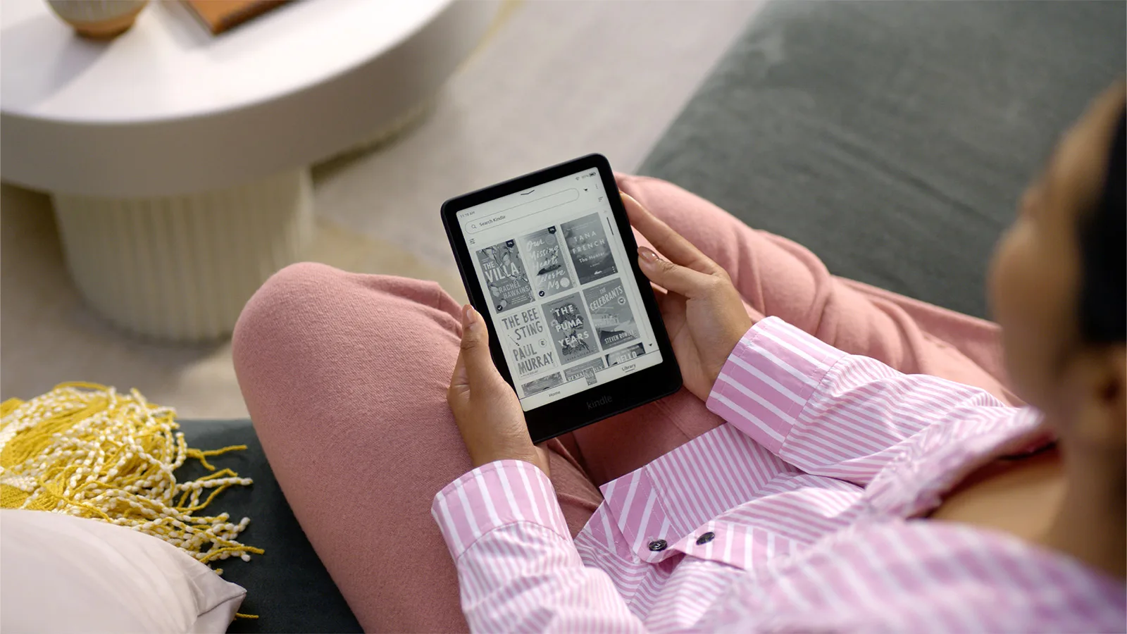 Lectrice tenant un Kindle Paperwhite noir, installée dans un canapé