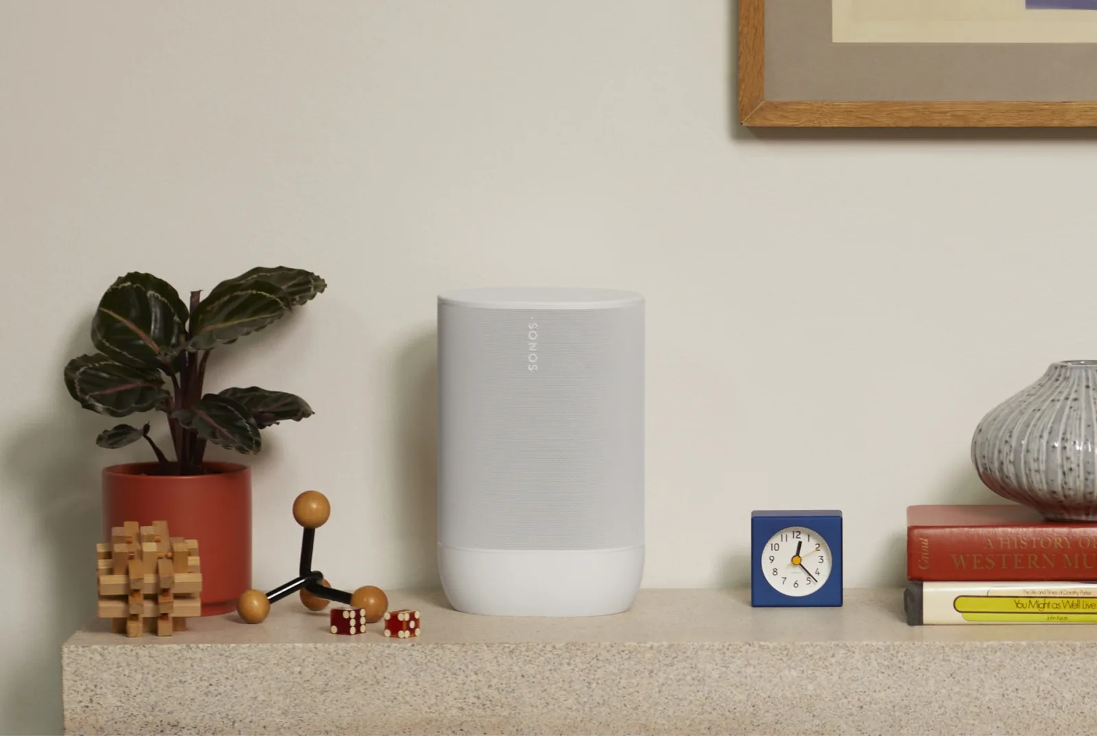 Enceinte Sonos Move 2 blanche posée sur un buffet à côté d'une plante